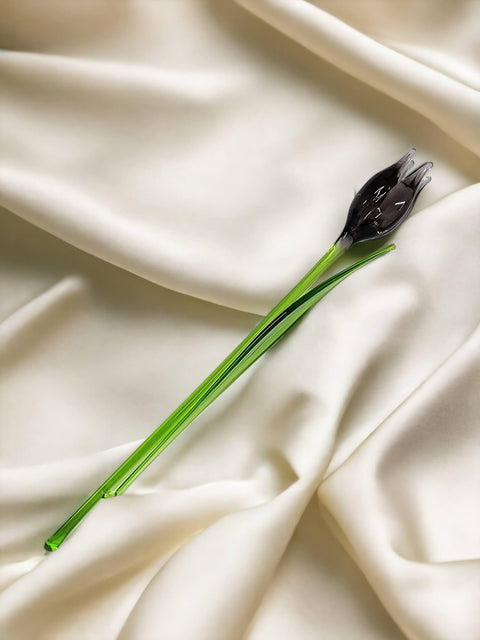 a single black flower on a white cloth