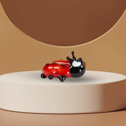 a lady bug figurine sitting on top of a white pedestal