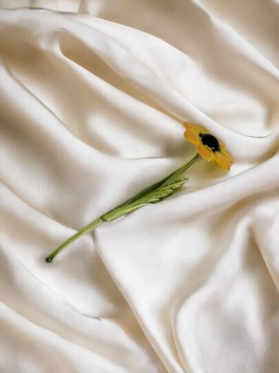 a single yellow flower laying on a white sheet