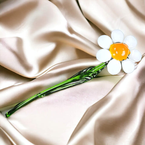 a white flower with a yellow center sitting on a satin surface