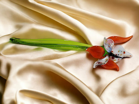 a red flower laying on top of a white cloth