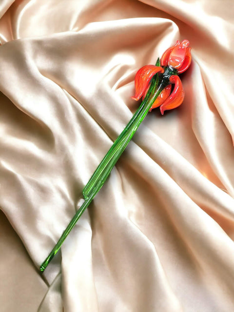 a red flower laying on top of a white sheet