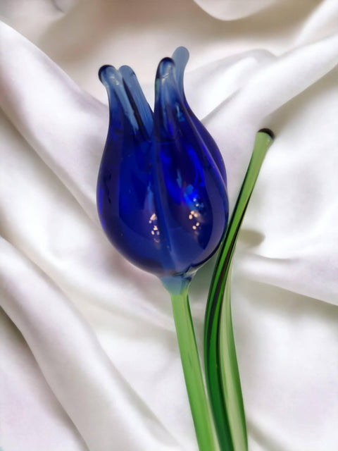 a blue glass flower sitting on top of a white sheet