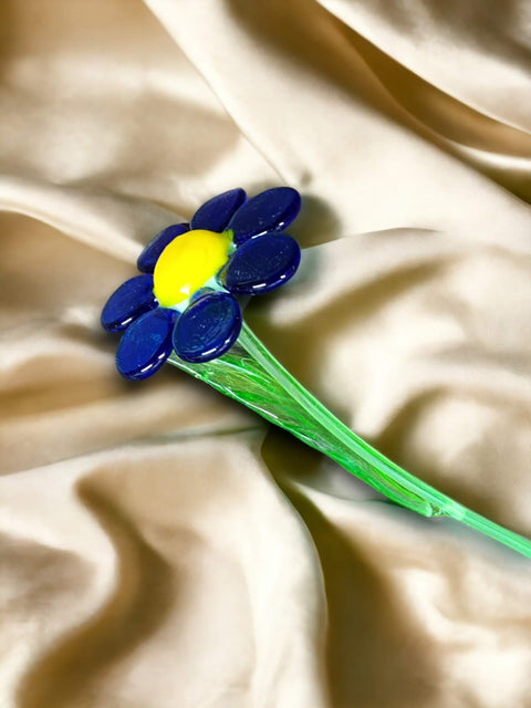 a single blue and yellow flower laying on a white cloth