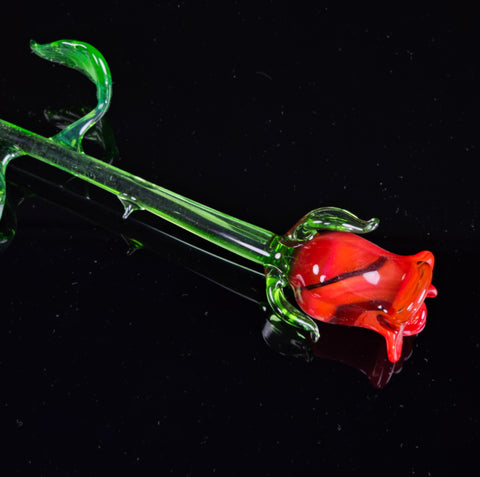 a red flower sitting on top of a glass pipe