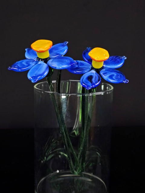 a glass vase filled with blue flowers on top of a table