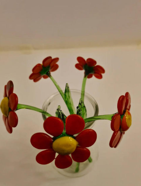 a glass vase filled with red flowers on top of a table